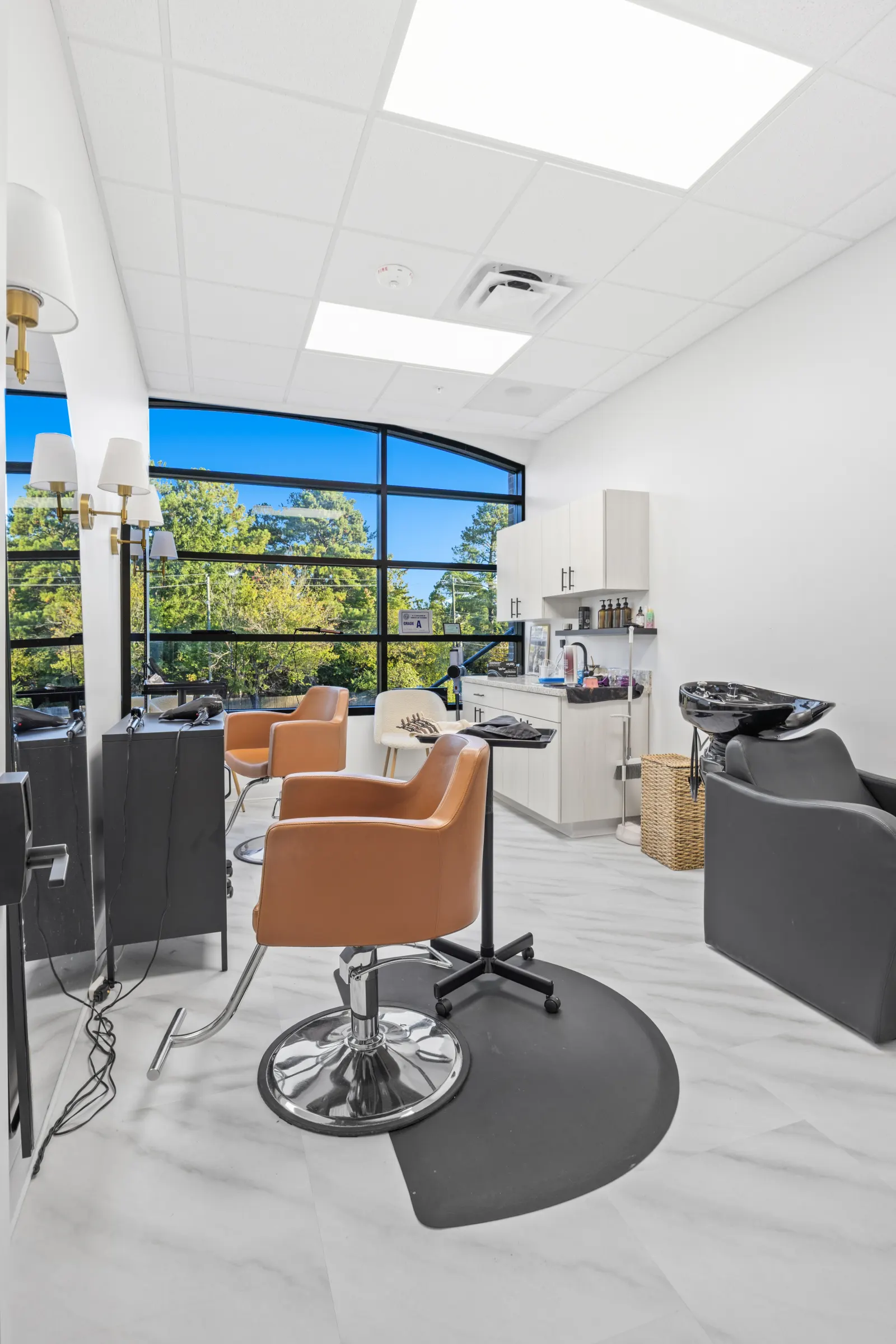 Private salon suite with a large window and two styling chairs at Revive Salon Collective